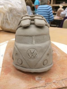 a close up of a clay object on a wooden table with people in the background