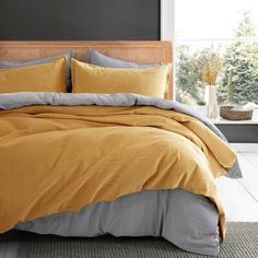 a bed with yellow and grey comforters in a room next to a large window