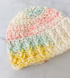 a multicolored crocheted hat sitting on top of a marble countertop