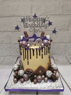 a birthday cake is decorated with chocolate and stars on the top, in front of a brick wall