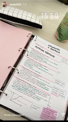 a pink binder sitting on top of a table next to a pen and notebook