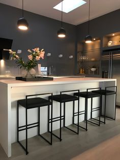 a kitchen with three stools and a center island in front of the counter top