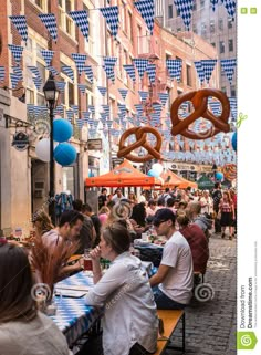 people sitting at tables in an outdoor food market with pretzels hanging above them