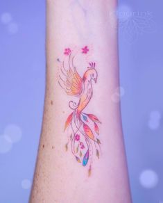 a colorful bird tattoo on the wrist