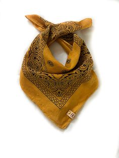 a yellow bandana with an intricate design on the front and side, sitting on a white surface