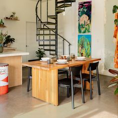 a spiral staircase in the middle of a dining room table with chairs and plates on it