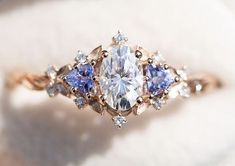 an engagement ring with three pear shaped diamonds and blue sapphires on it's sides