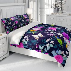 a bedroom with white furniture and flowers on the bedspread, along with two nightstands