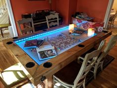 a table that has some books on it with candles in front of it and two chairs next to it