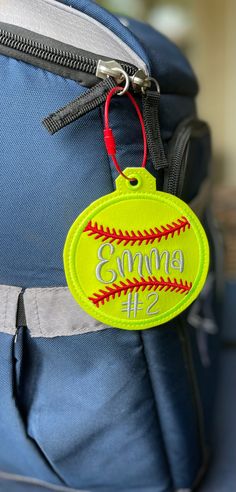 a back pack with a baseball ornament hanging from it's front pocket