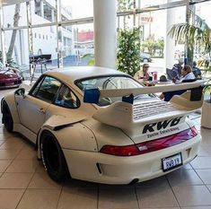 a white car parked inside of a building with people sitting at tables in the background