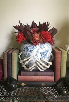 a blue and white vase with flowers on top of books