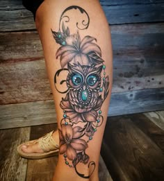 a woman's leg with an owl and flower tattoo design on the side of her thigh