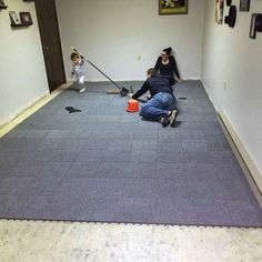 a woman and child are cleaning the floor with brooms in an empty room,