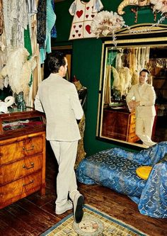 a man standing in front of a mirror next to a dresser