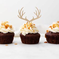 three cupcakes with frosting and antlers on top