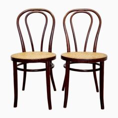 two wooden chairs with wicker seats are shown side by side on a white background