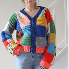 a woman wearing a multicolored cardigan standing in front of a stair case