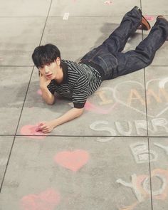 a young man laying on the ground with his hand to his face and writing in chalk