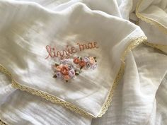 a close up of a white cloth with embroidered words on it and flowers in the middle