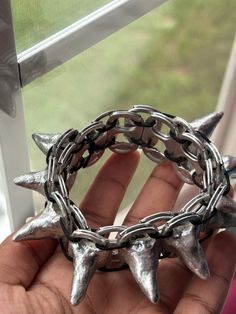 a hand holding a metal ring with spikes on it's sides and chains around the edges