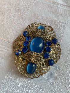 Gorgeous old Czech glass sash pin/brooch  Gold tone filigree setting with sapphire blue stones and cabochons  In very good condition, some discolouration on the back  It measures 6.2 cm x 5.2 cm Nice collectors piece Elegant Blue Jeweled Brooches, Elegant Blue Oval Brooches, Elegant Oval Blue Brooches, Blue Victorian Brooches For Formal Occasions, Blue Victorian Brooch For Formal Occasions, Victorian Blue Brooch For Formal Occasions, Blue Oval Brooch For Formal Occasions, Blue Cabochon Brooch For Formal Occasions, Blue Cabochon Brooches For Wedding