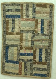 an old patchwork quilt hanging on the wall in front of a white wallpaper