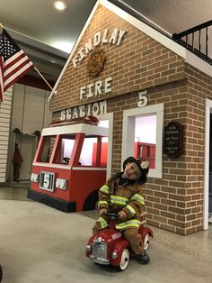 a fireman sitting on top of a toy fire truck in front of a building