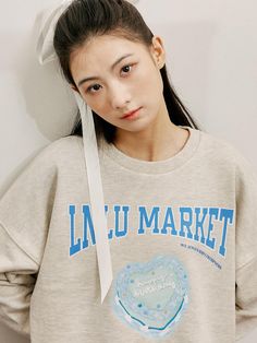 This is a crewneck sweatshirt with a relaxed fit, featuring ribbed cuffs and a hemline that suggests a cozy, casual garment. The front is adorned with a playful graphic that reads LNL MARKET in bold letters, accompanied by an image of a heart-shaped object with the brand's name. The graphic combines a sense of whimsy with a casual market theme, potentially appealing to a young, fun-loving demographic. The sweatshirt's overall design is perfect for laid-back days or as a comfortable statement piece.- The heart-shaped graphic adds a cute and loving touch to the sporty sweatshirt.- The contrasting graphic against the heathered material stands out, making it a focal point of the design.- Its design is both trendy and functional, easily becoming a go-to piece in a casual wardrobe. Lettering Sweatshirt For Spring Streetwear, Casual Lettering Sweatshirt For Spring, Crew Neck Sweatshirt With Text Print For Spring, Relaxed Fit Lettering Sweatshirt For Spring, Spring Crew Neck Sweatshirt With Text Print, Spring Lettering Sweatshirt Relaxed Fit, Relaxed Fit Sweatshirt With Lettering For Spring, Spring Cotton Sweatshirt With Lettering, Casual Crew Neck Sweater With Slogan