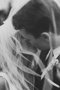 a bride and groom are kissing under veils