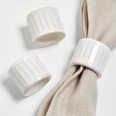 two white napkin holders sitting next to each other on top of a cloth covered table