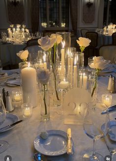 the table is set with white roses and candles