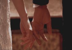 the hands of two people holding each other's hand in front of a wall