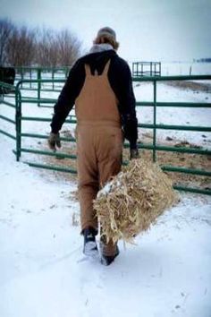 a man walking in the snow carrying hay