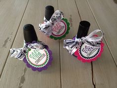 three black and white nail polish bottles with ribbons tied around them on a wooden surface