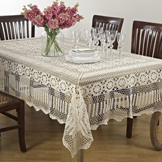 the table is set for four with white flowers in vases and plates on it