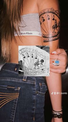 a woman with tattoos on her arm holding up a card that says playing cards in front of her back