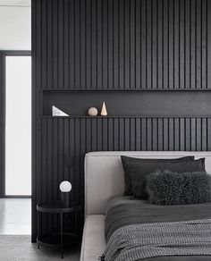 a black and white bedroom with a bed, night stand and lamp on the wall