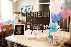 a baby shower party with balloons, cake and candy on the counter in front of a sign that says game on