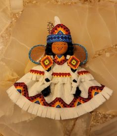 a small doll is sitting on a marble surface with an orange and blue headdress