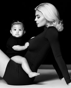 a woman is holding a baby in her lap and posing for a black and white photo