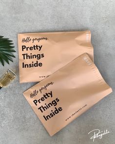 two packets of pretty things inside next to a potted plant on the floor with an ad for pretty things inside