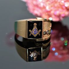 A gentleman's 10 karat yellow gold Masonic ring with a 10 millimeter by 8 millimeter rectangular black onyx and 2 symbols on one side.  This ring is size 10 Symbolic Black 14k Gold Jewelry, Symbolic Black Engraved Hallmarked Ring, Black Symbolic Hallmarked Signet Ring, Black Symbolic Signet Ring With Polished Finish, Masonic Ring, Estate Jewelry, Black Onyx, Onyx, Size 10