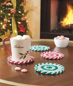 red and white coasters on a table with hot chocolate in front of a christmas tree