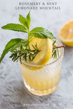 a lemon and rosemary cocktail garnished with fresh mint on a gray tablecloth