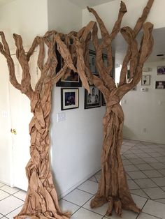 two trees made out of brown paper sitting on top of a tiled floor next to a wall