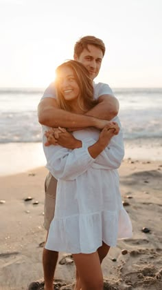 a man and woman hugging on the beach