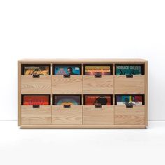 a wooden cabinet filled with lots of books on top of white floor next to wall