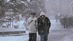 two people walking in the snow on a street