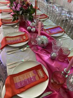 the table is set with silverware and pink napkins for an elegant dinner party